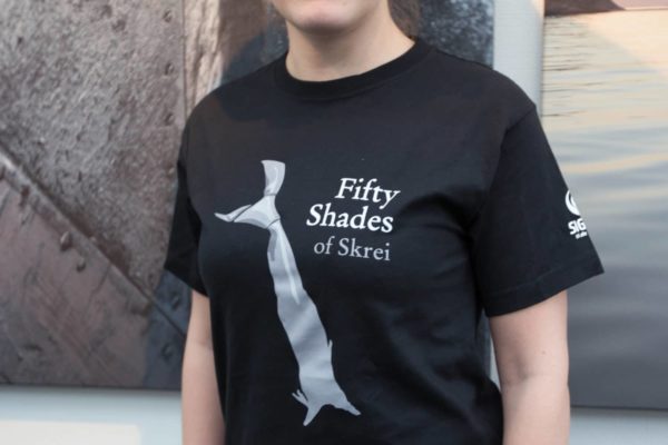 Sort T-skjorte med teksten "Fifty Shades of Skrei" og bilde av en tørket fisk
