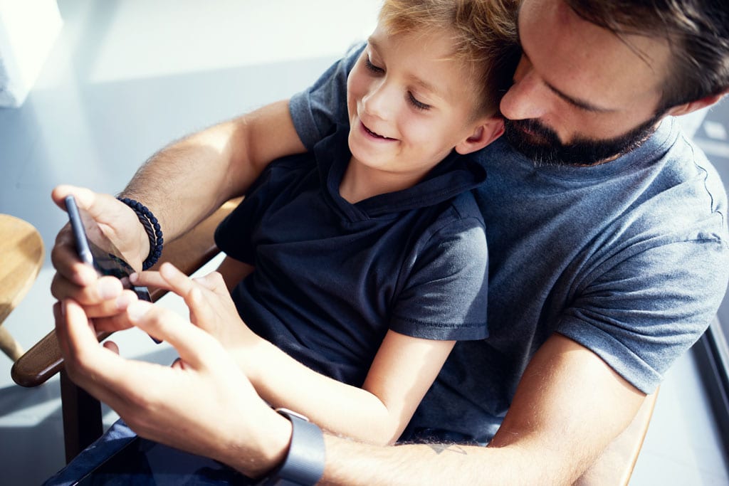 Far har sønn på fanget mens de ser på telefonen sammen