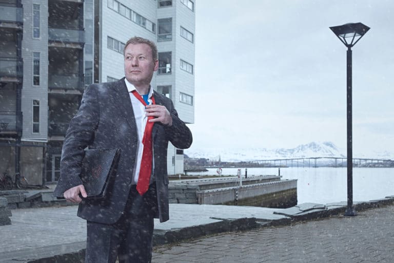 Mats fra Signal Bredbånd er ikledd dress og står ute i snøværet i Bodø, på vei til kundemøte