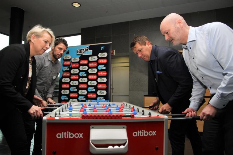 Komersielle ledere fra Norsk Toppfotball og Altibox smiler fremfor sin fornyede sponsortavle