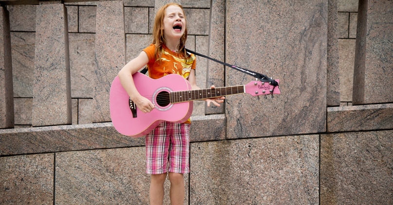 Liten jente med rosa gitar synger for full hals