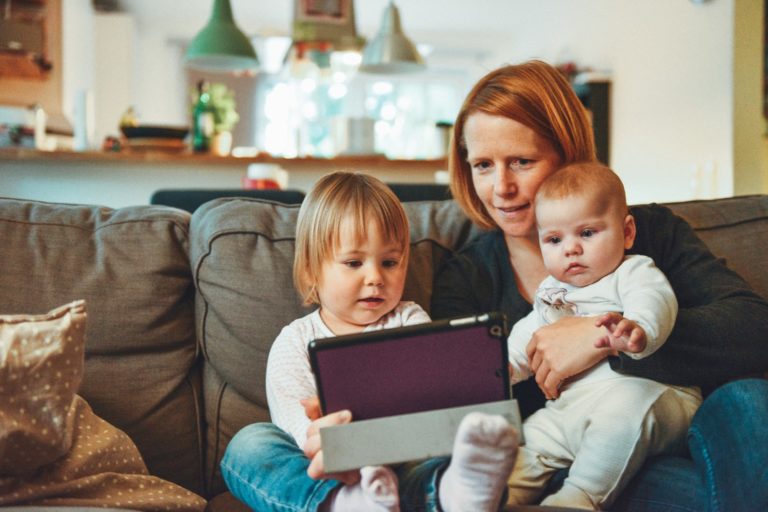 Mor og to barn koser seg i sofaen med ipad og film