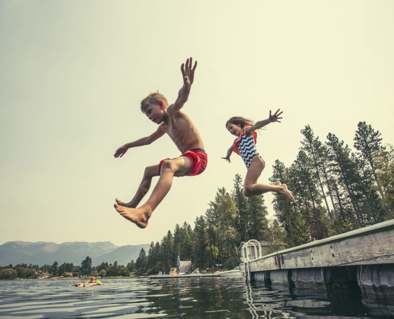 To barn tar sats og hopper fra en brygge og ned mot vannet