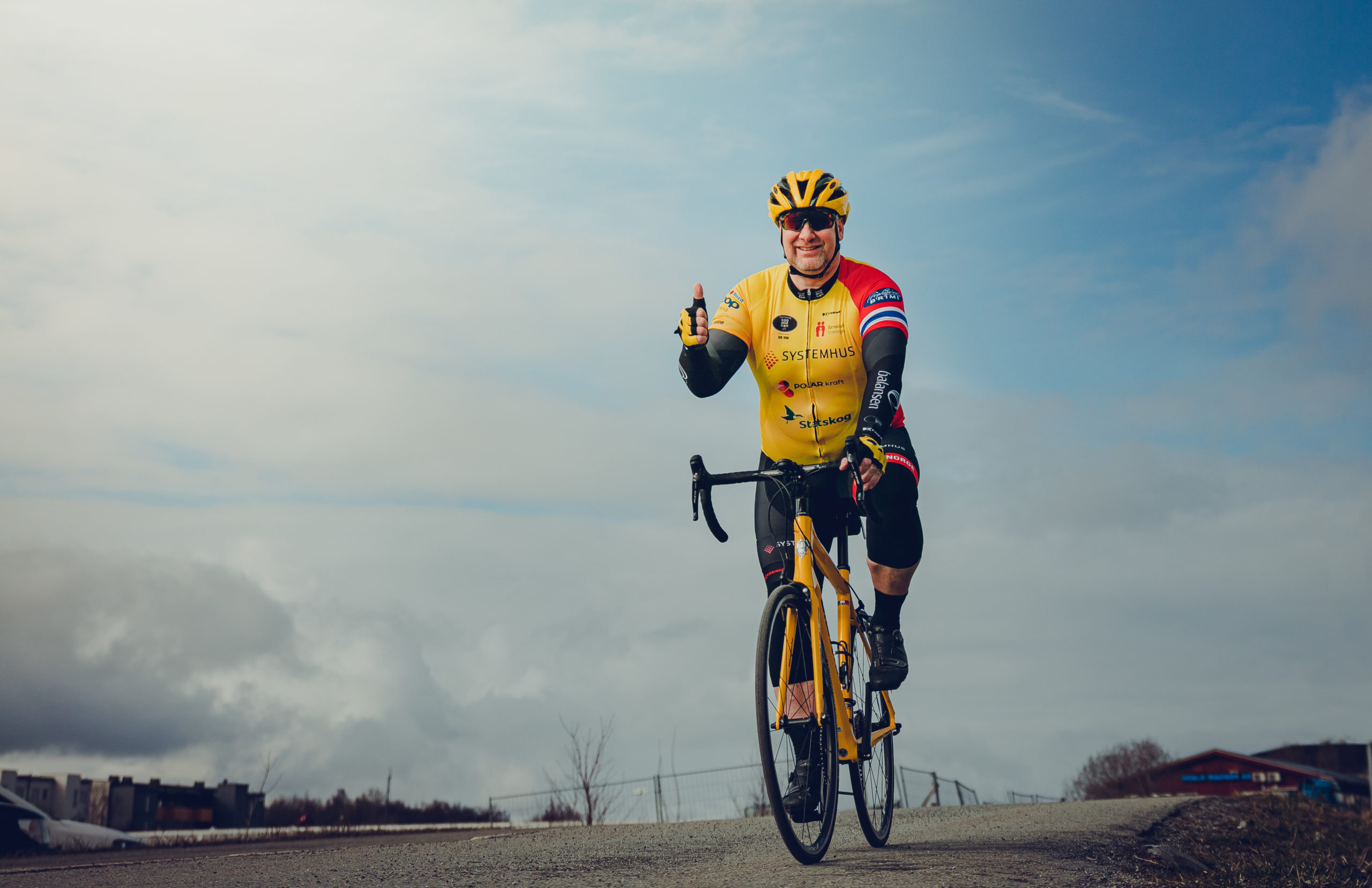 Valter Jacobsen ikledd gul sykkeldrakt sykler mot kamera på racingsykkel med tommel opp