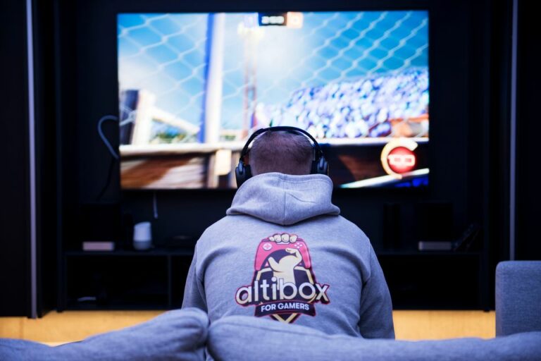Gutt sitter foran tv-skjermen og gamer, med grå altibox-genser på