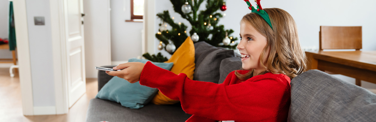 Julepyntet jente retter fjenkontrollen mot tv i spenning når hun slår på julefilm