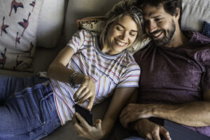 En dame og en mann som smiler og ser på en mobil